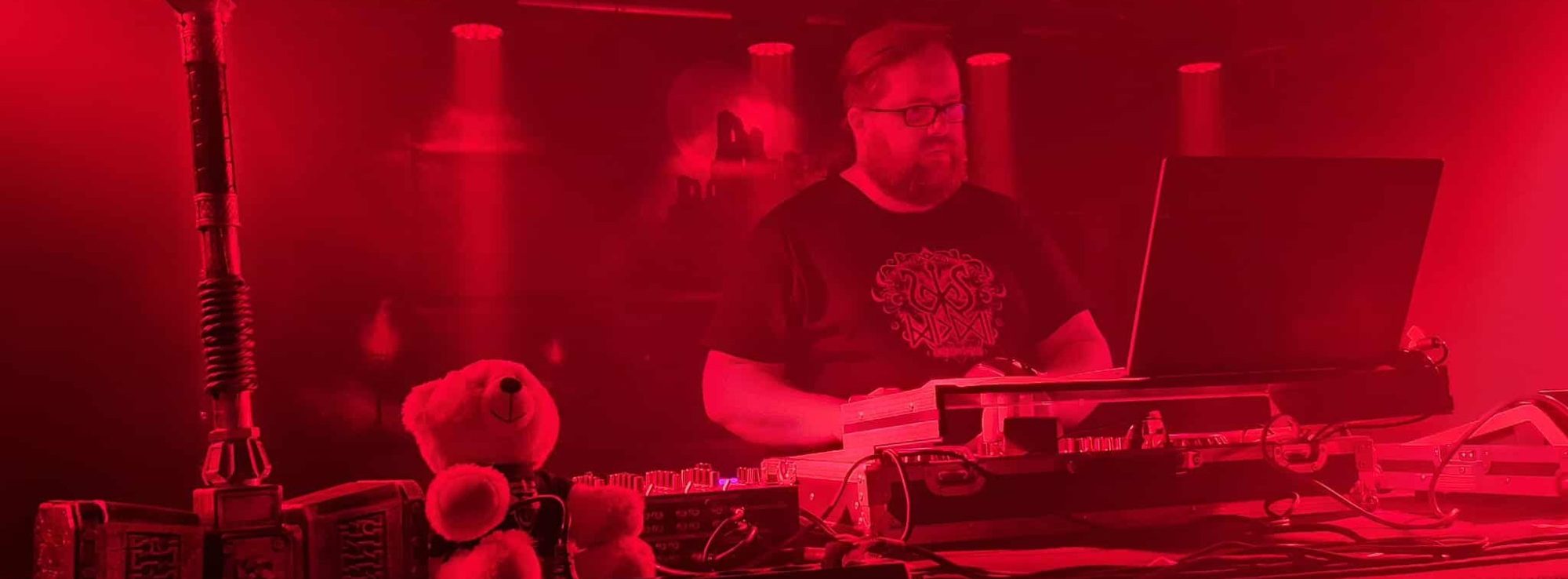 DJ MicDi steht an einem Mischpult DJ MicDi steht an einem Mischpult mit bunten Lichtern und hebt die Hände.